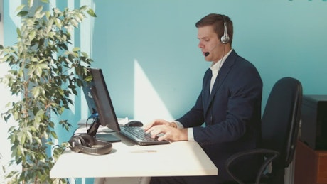 Man in a suit working in an office with a plant.