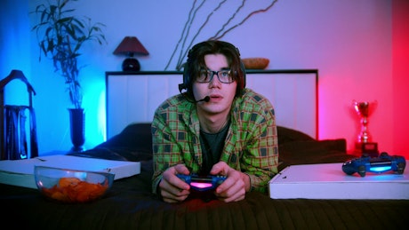 Man in bed playing video games online