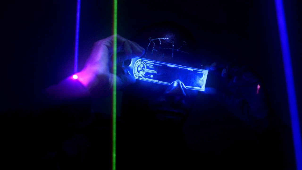 Man in cyberpunk outfit sta LIVE DRAW nds under laser lights
