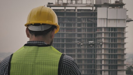 Man in hard hat watching drone fly.