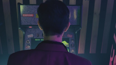 Man in suit playing on arcade machine