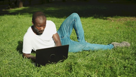 Man learning online while relaxing in park