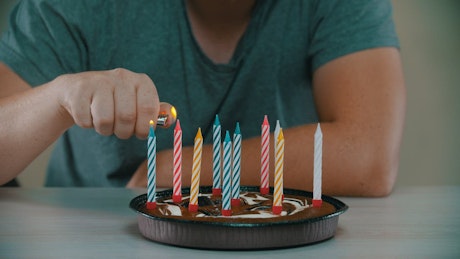 Man lighting candles on a small birthday cake