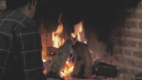 Man lighting fireplace with firewood