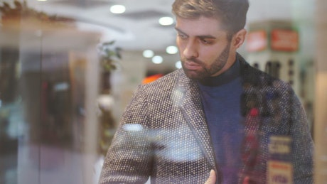 Man looking at the sideboard of a clothing store.