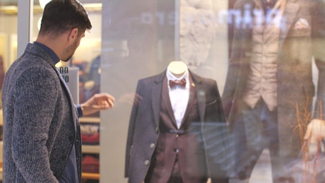 Man looking at the sideboard of a suit store.