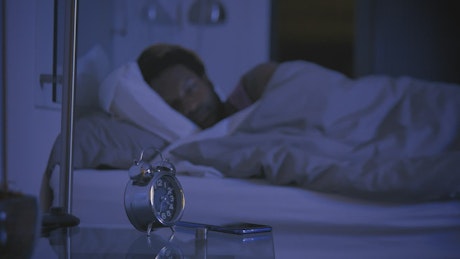 Man lying down moving a lot because of not being able to sleep.