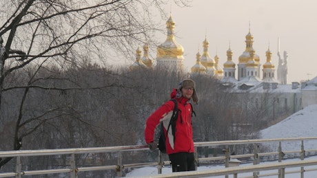 Man on a bridge in a snowy city