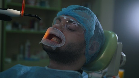 Man on a teeth whitening procedure with the dentist.