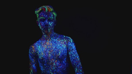 Man painted in fluorescent paint posing for the camera.