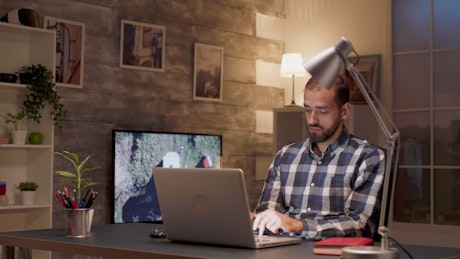 Man pauses to think while working on laptop.