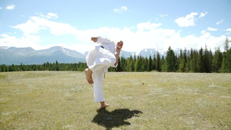 Man performing a fighting stance on an open field.