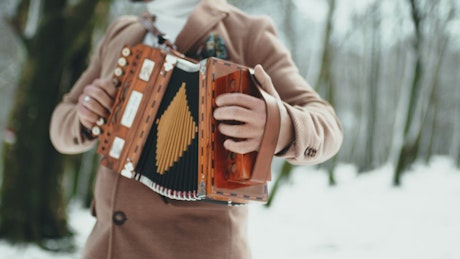 Man playing accordion in the park during winter time.