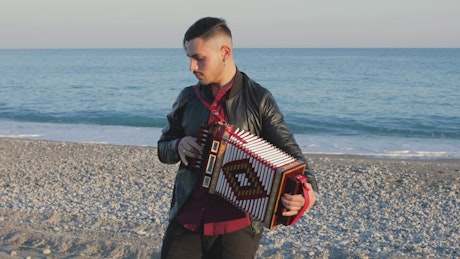 Man playing music with accordion on the beach.