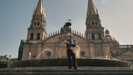 Man plays an accordion in front of a fountain