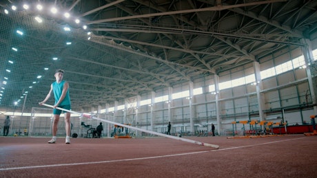Man practicing pole vault in a sports center.