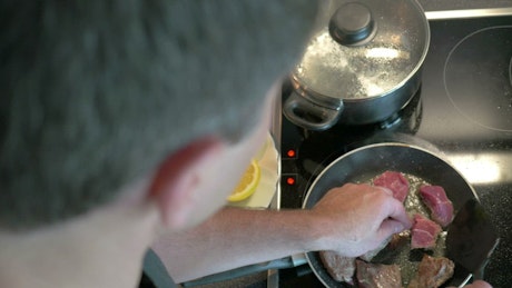 Man preparing beef in a frying pan