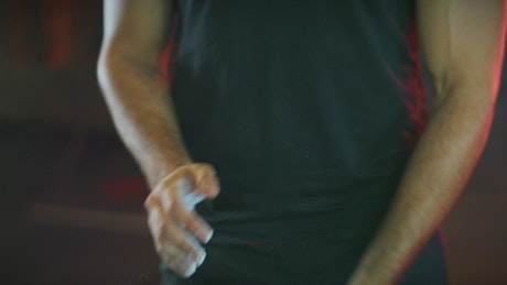 Man putting chalk on hands for push-ups.