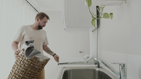 Man putting clothes in a washing machine at home.