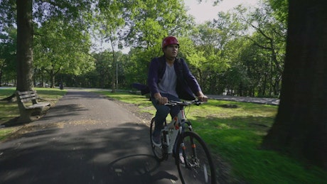 Man riding a bike through the park.