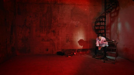 一名男子坐在被武器包围的刑讯室里