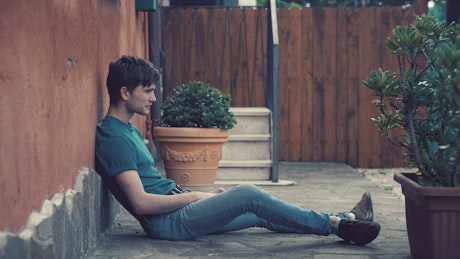 Man sits on the ground outside in heartbreak.
