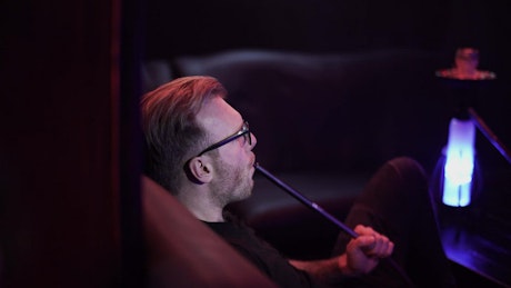 Man smoking alone in hookah club.