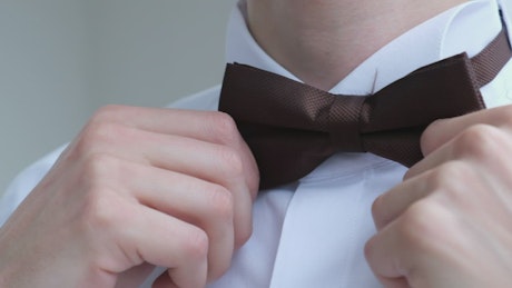 Man straightens his bow tie.