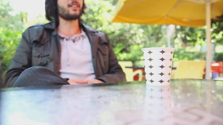 Man talking drinking coffee outside.