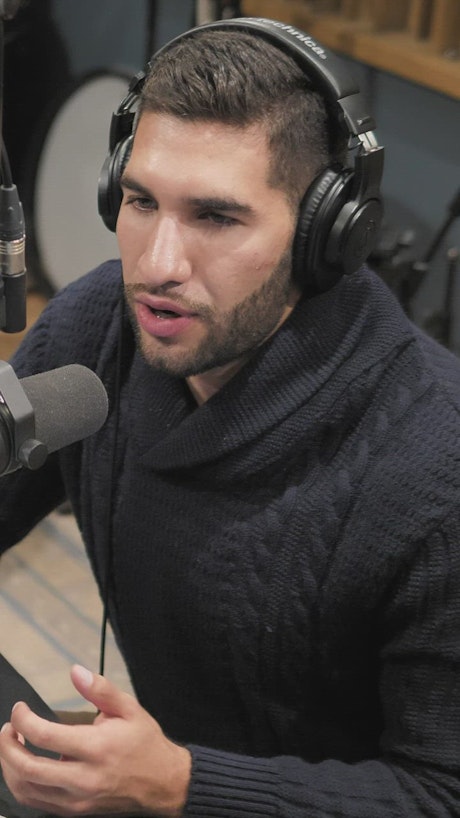 Man talking in front of a radio station microphone.