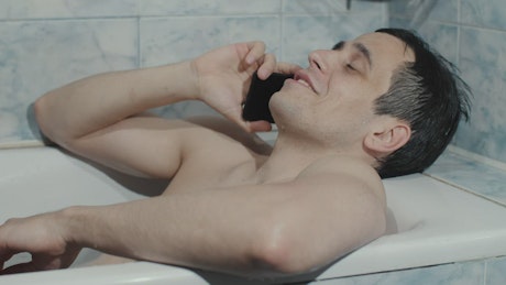 Man talks on the phone in the bathtub