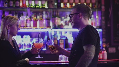 Man talks to woman at bar in nightclub.