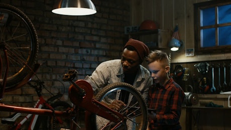 Man teaching a boy bicycle maintenance