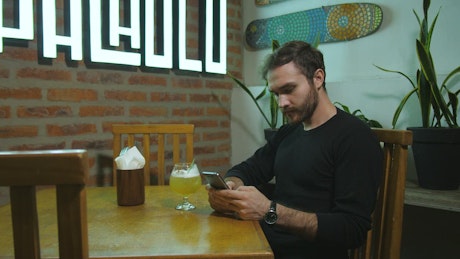 Man texting in a bar.