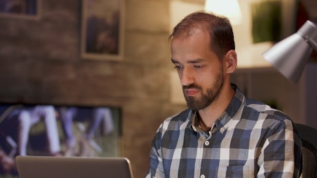 Man thinks hard while working on laptop from home
