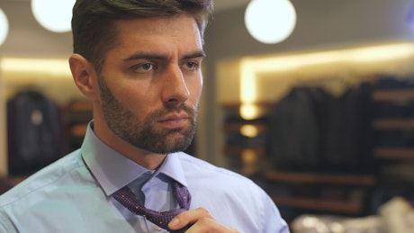 Man ties his tie in suit shop