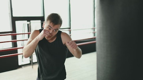 Man training on punching bag in boxing ring