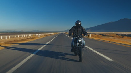 Man traveling by motorcycle on an empty road.