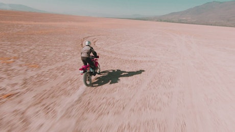Man traveling through the desert on his motorcycle.