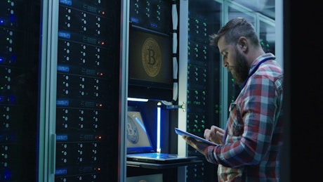 Man using laptop on bitcoin mining farm.