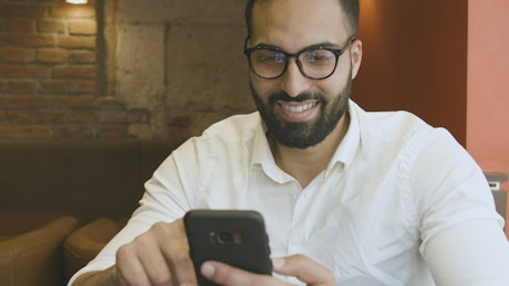 Man using mobile app reflected in glasses.