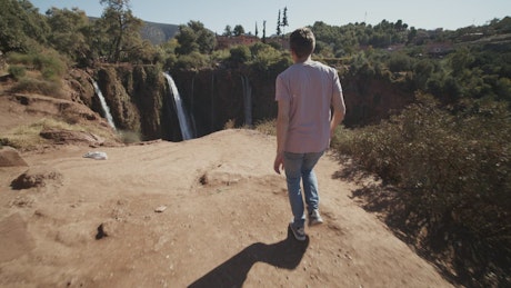 Man walks to a deep canyon with waterfalls