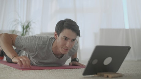 Man watching exercises on a tablet to practice them.