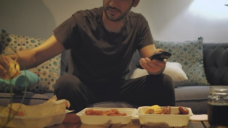 Man watching TV and eating fast food.