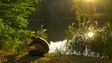 Man with a lap top on the shore of a lake