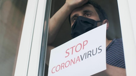 Man with mask and a sign against the coronavirus