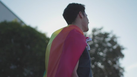 Man with pride rainbow flag around his neck.