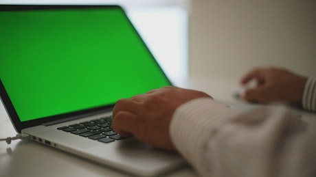 Man working on a laptop with a green screen