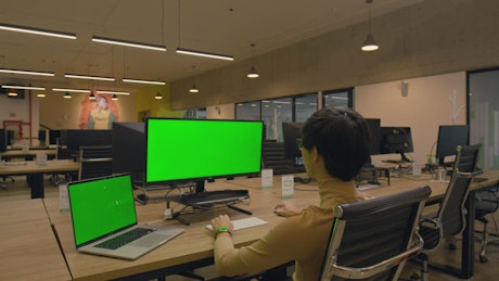 Man working on computer with chroma green background.