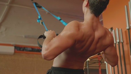 Man working out with straps in a gym